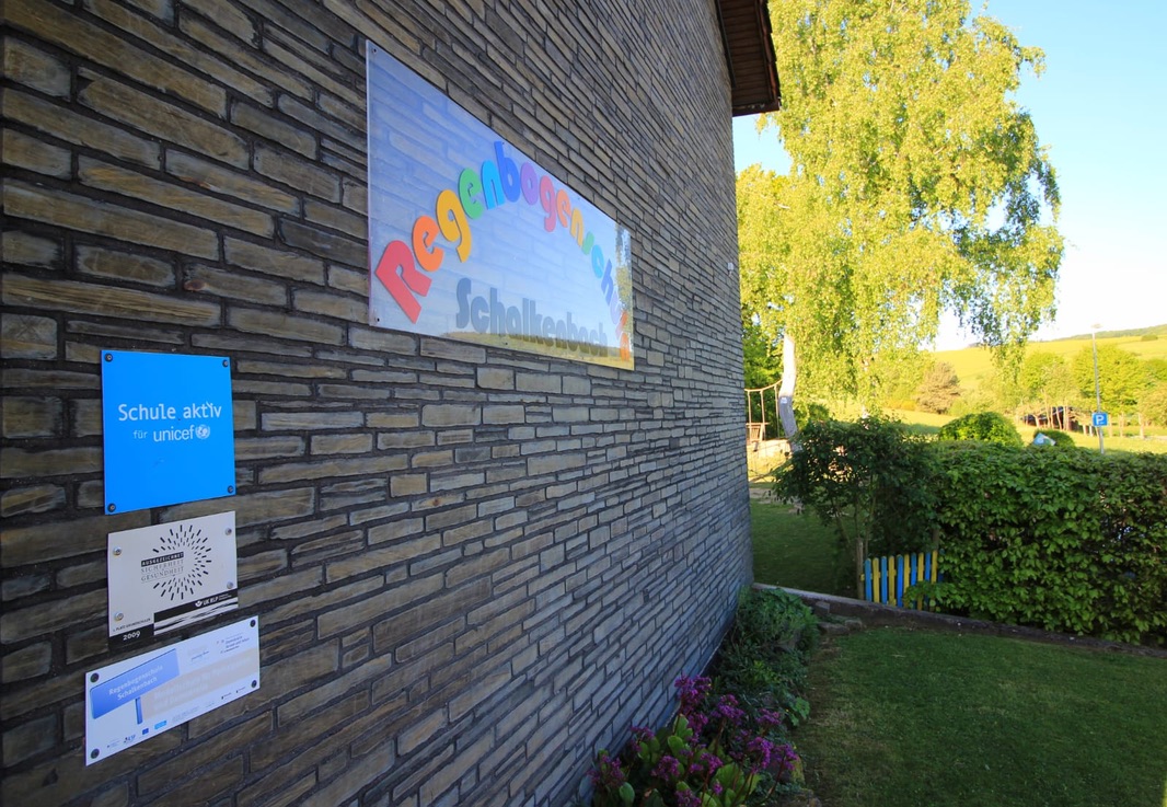 Fassade der Schule mit dem Schulschild und der Plakette Schule aktiv für UNICEF